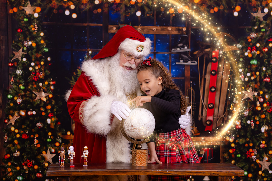girl pointing to globe with magic appearing during her photo session with Santa in Rolesville North Carolina in Wake County
