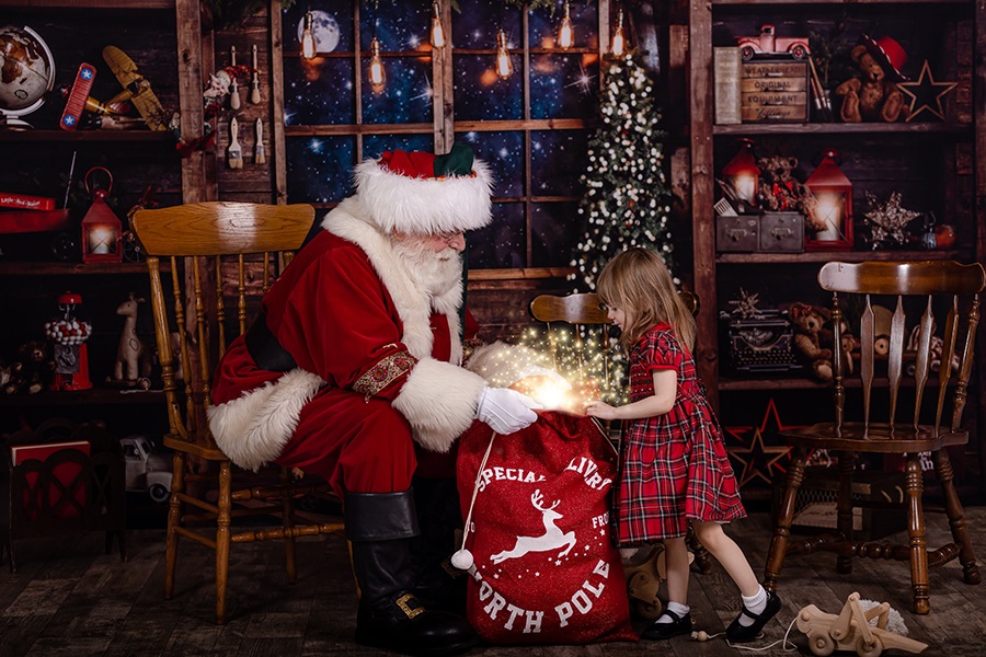 little girl looking into santa's toy bag during a private photo session with Santa in Wake County NC